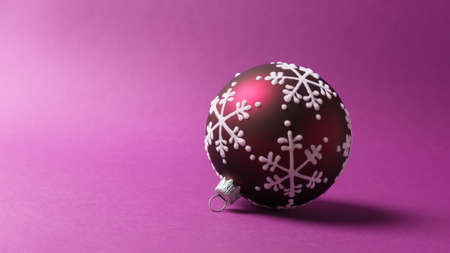 Christmas or New Year decoration. Closeup of beautiful red christmas ball on purple background with copy spaceの写真素材