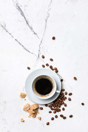 Top view of black coffee in white cup with cane lump sugar for breakfast on marble backgroundの写真素材