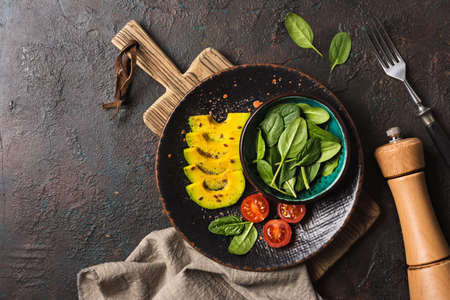 Top view of healthy and tasty vegetarian food. Salad with fresh baby spinach leaves, cherry...