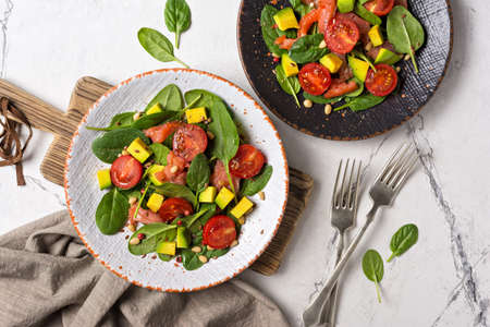 Top view of healthy and tasty food. Salad with fresh baby spinach leaves, cherry tomatoes, sliced...