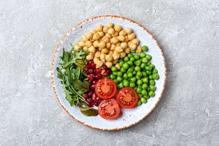 Healthy and tasty food on plate. Top view of vegetarian salad with chickpeas, mix of fresh leaves,...