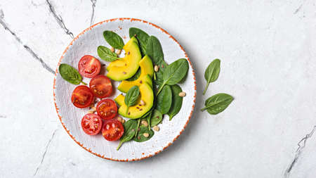 Top view of healthy and tasty vegetarian food. Salad with fresh baby spinach leaves, cherry...