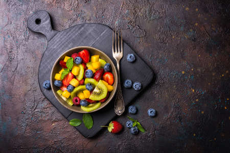 Natural organic food for healthy and dieting life. Fresh fruit salad with kiwi, strawberry, blueberry, raspberry, peach and mint on dark concrete backgroundの写真素材