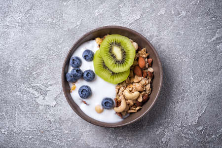 Organic food for healthy and dieting breakfast.Top view of bowl with granola, yogurt, fresh kiwi,...