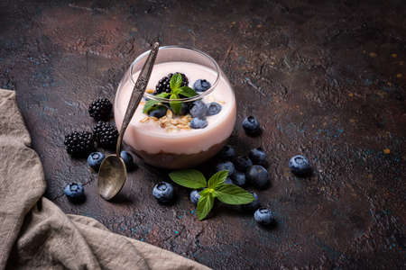Tasty chocolate pudding or sweet mousse with yogurt, blueberry, blackberry and mint in portion glass on dark concrete backgroundの写真素材