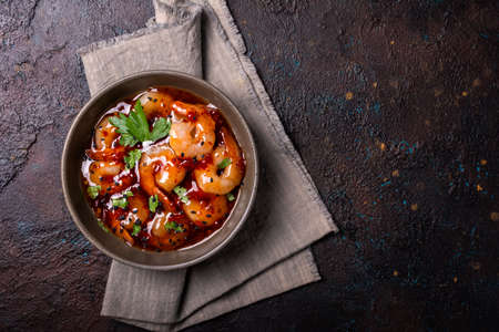 Top view of bowl with spicy shrimps in sweet chili asian sauce with black sesame seeds on dark concrete backgroundの写真素材