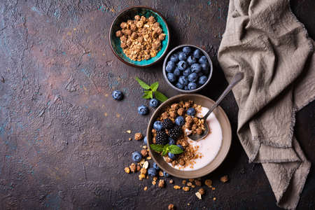 Organic food for healthy and dieting breakfast.Top view of bowl with granola, yogurt, fresh blueberry, blackberry and mint on dark concrete backgroundの写真素材
