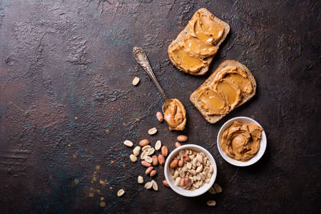 Sweet peanut paste or butter with honey on bread for tasty breakfast on dark concrete backgroundの写真素材