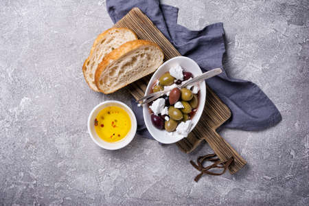 Top view of tasty olives mix with Feta cheese and slices of bread on grey concrete backgroundの写真素材