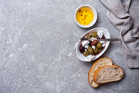 Top view of tasty olives mix with Feta cheese and slices of bread on grey concrete background with copy spaceの写真素材