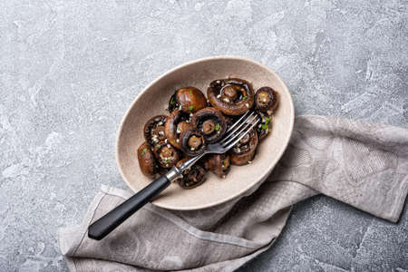 Top view of grilled champignon mushrooms in bowl with spice on grey concrete backgroundの写真素材