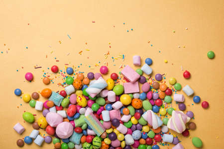 Multicolored sweet and bright dragee, candies, lollipops, marshmallows for fun party on golden...