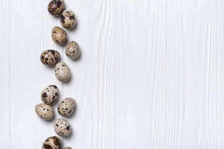 Top view of small quail eggs on white wooden background with copy spaceの写真素材