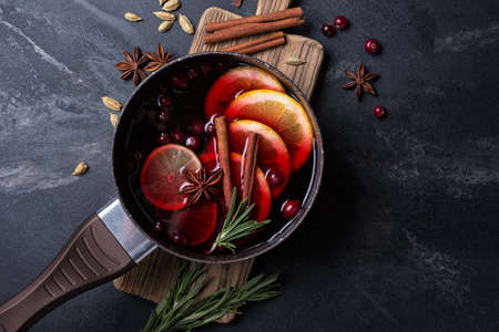 Autumn or christmas traditional drink with apples, oranges, cranberry, cinnamon, rosemary and other ingredients on black marble backgroundの写真素材