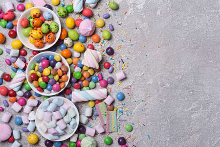 Multicolored sweet and bright dragee, candies, lollipops, marshmallows for fun party on grey...