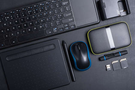 Top view of designer work place with graphics tablet, memory card, keyboard, portable hard drive on...