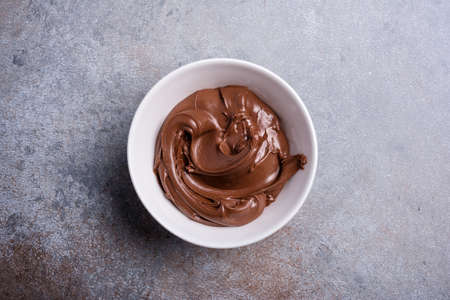 Delicious chocolate cream or brown nut butter, paste as ingredient for tasty homemade dessert on concrete backgroundの写真素材