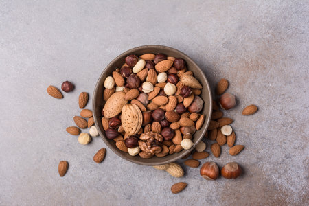 Top view of bowl with almond, hazelnut, walnut and peanut nuts on grey concrete backgroundの写真素材