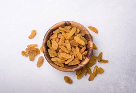 Top view of wooden bowl with raisins as ingredient for tasty and healthy meals on grey concrete backgroundの写真素材