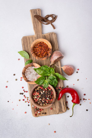 Top view of peppercorn, salt, garlic, basil and red hot chilli pepper for spicy and aromatic food on grey concrete backgroundの写真素材