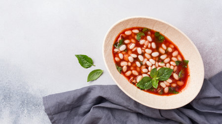 Top view of spicy dish with beans in tomato sauce with fresh basil on grey concrete backgroundの写真素材
