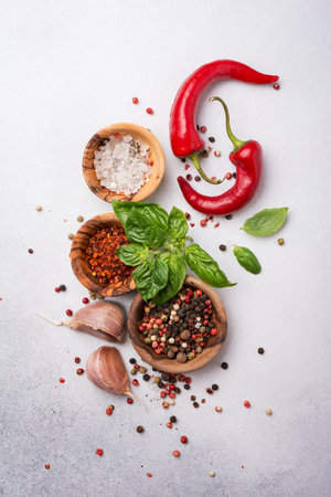Top view of peppercorn, salt, garlic, basil and red hot chilli pepper for spicy and aromatic food on grey concrete backgroundの写真素材