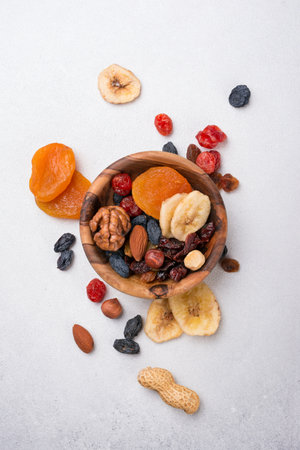Top view of wooden bowl with dried fruit, berries and nuts as ingredient for tasty and healthy meal on grey concrete backgroundの写真素材