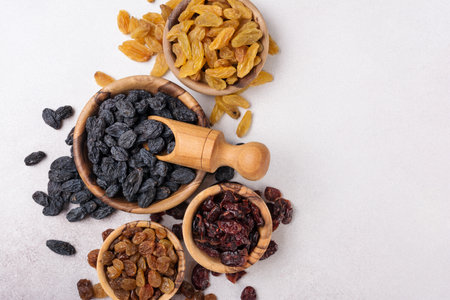 Top view of wooden bowls with raisins and dried cranberries as ingredient for tasty and healthy meal on grey concrete backgroundの写真素材