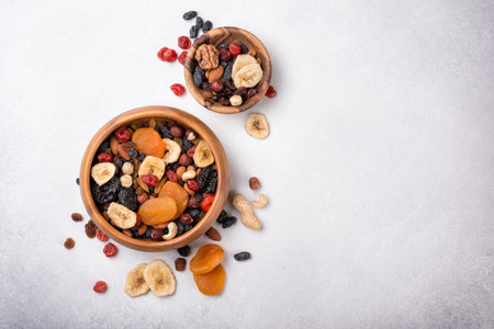 Top view of wooden bowls with dried fruit, berries and nuts as ingredient for tasty and healthy meal on grey concrete backgroundの写真素材