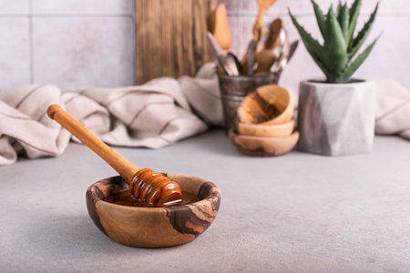 Wooden bowl with healthy organic honey and dipper on the table and kitchen backgroundの写真素材