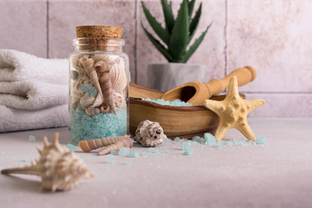 Blue sea salt in wooden bowl with shells and white towels for relax, bath, spa on tile backgroundの写真素材