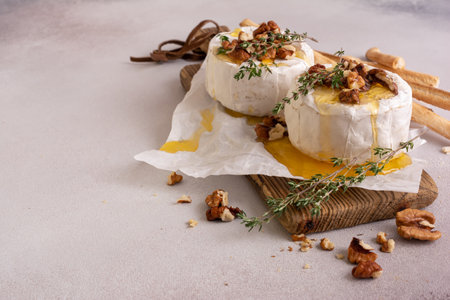 Gourmet meal of white brie cheese or camembert with thyme, walnut, honey and grissini bread stick for tasty dinnerの写真素材