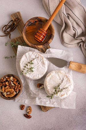 Gourmet appetizer of white brie cheese or camembert with thyme, walnut and honey on grey concrete backgroundの写真素材