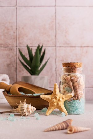 Blue sea salt in wooden bowl with shells and white towels for relax, bath, spa on tile backgroundの写真素材