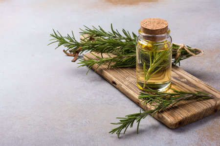 Glass bottle with oil and fresh rosemary kitchen herbs for spicy food on grey concrete backgroundの写真素材