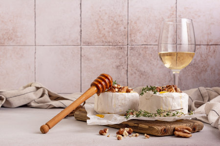 Gourmet meal of white brie cheese or camembert with thyme, walnut, honey and glass of white wine for tasty dinnerの写真素材