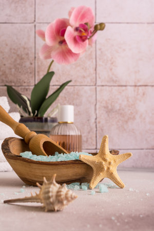 Blue sea salt in wooden bowl with shells, orchid flower and white towels for relax, bath, spa on tile backgroundの写真素材