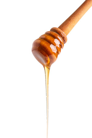Healthy organic honey pouring with a wooden dipper isolated on white backgroundの写真素材