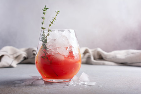 Homemade ice citrus fruit cocktail or mocktail with grapefruit slice in glass for tasty and refreshing break on grey kitchen backgroundの写真素材