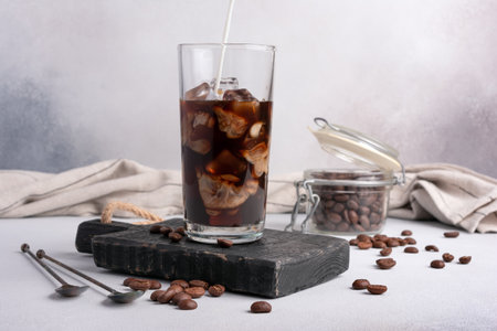 Homemade ice latte. Black coffee with ice and milk or cream in glass for tasty and refreshing break on grey kitchen backgroundの写真素材