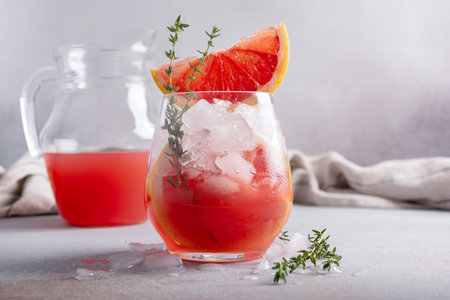 Homemade ice citrus fruit cocktail or mocktail with grapefruit slice in glass for tasty and refreshing break on grey kitchen backgroundの写真素材