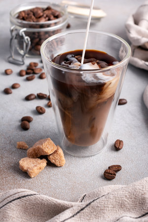 Homemade ice latte. Black coffee with ice and milk or cream in glass for tasty and refreshing break on grey kitchen backgroundの写真素材