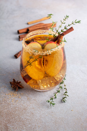 Homemade ice sweet apple cider, cocktail or mocktail with cinnamon, thyme and anise in glass for tasty and refreshing break on grey concrete backgroundの写真素材