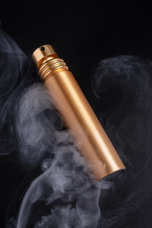 Mock-up of cosmetic product. Golden modern bottle of perfume with smoke on black backgroundの写真素材