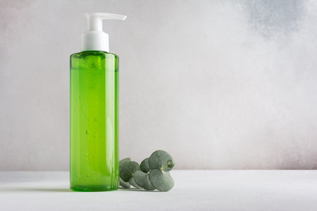 Transparent dispenser with green shampoo or shower gel and eucalyptus branch. Mockup for natural cosmetics and body careの写真素材