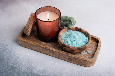Blue sea salt in wooden bowl with candle and eucalyptus for relax, bath, spa on grey concrete backgroundの写真素材