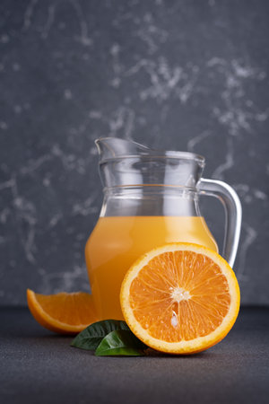 Glass jug of fresh orange juice with ripe orange fruitsの写真素材