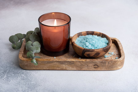 Blue sea salt in wooden bowl with candle and eucalyptus for relax, bath, spa on grey concrete backgroundの写真素材