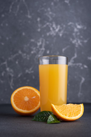 Fresh orange juice in glass with ripe orange fruits on dark backgroundの写真素材