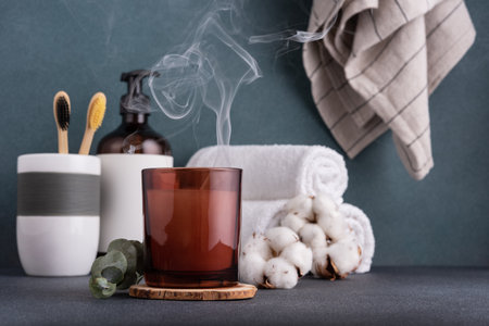 Scented candle and bathroom accessories: towels, dispenser and bamboo toothbrush. Modern bathroom dÃ©cor.の写真素材